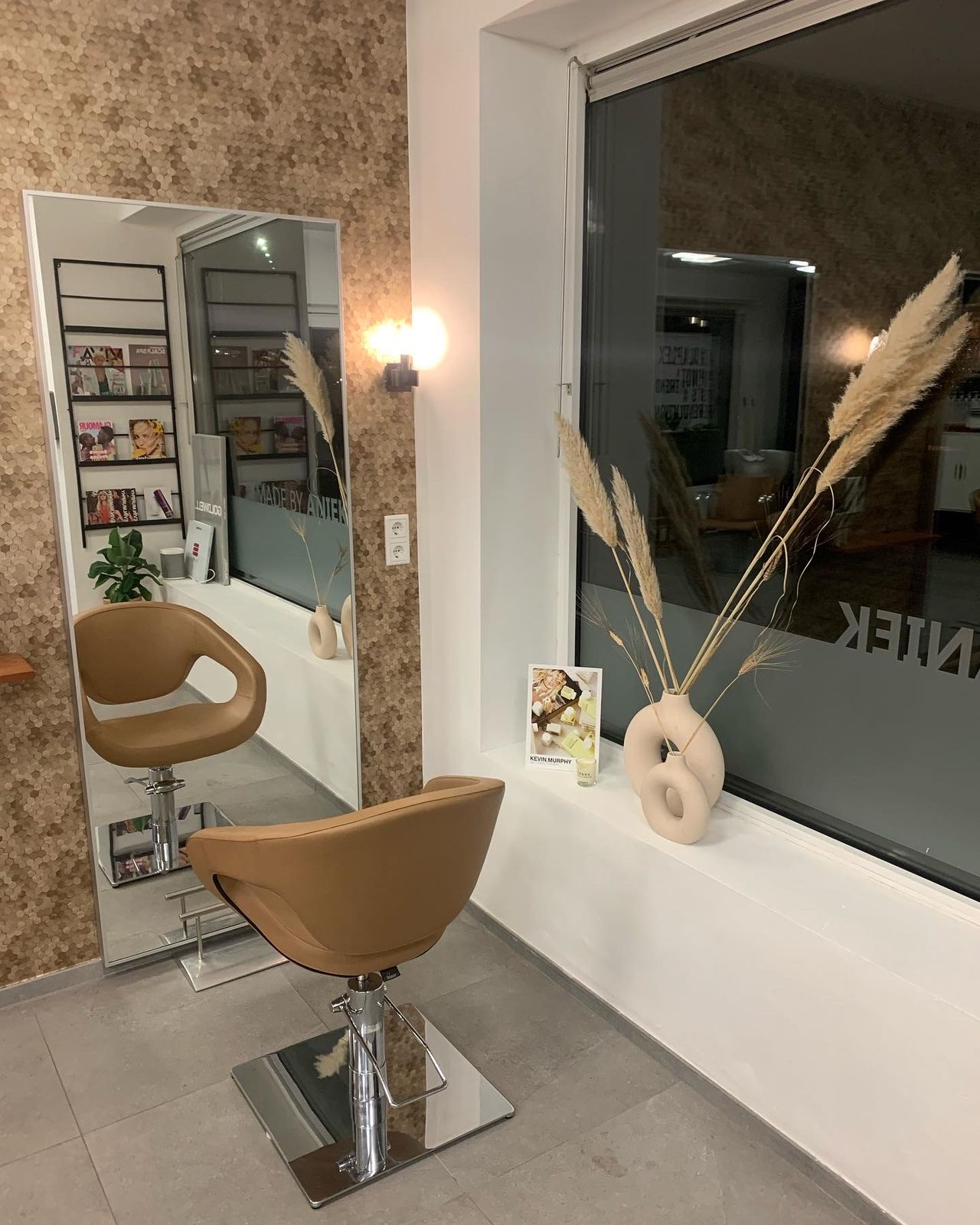 De salon: cognackleurige stoelen voor een spiegel op een wand van zeshoekige tegels